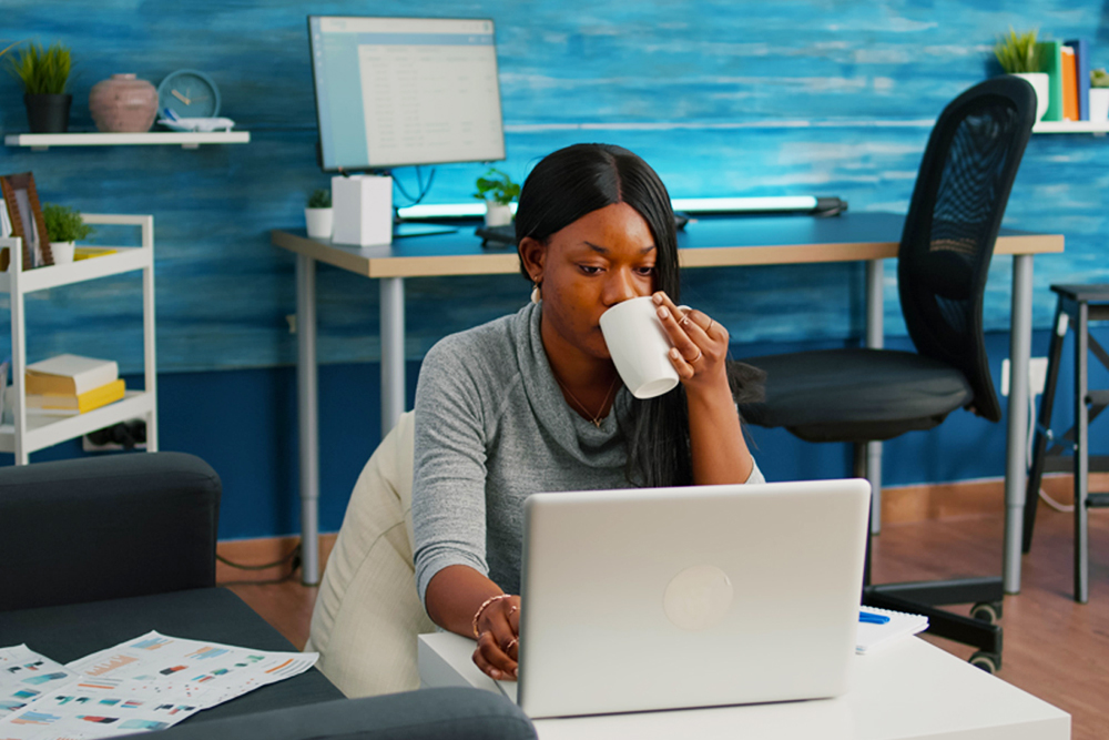 black-student-drinking-coffee-typing-social-media-article-browsing-lecture-communication-webinar-laptop-working-living-room